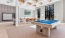 a clubhouse room with a pool table and large windows