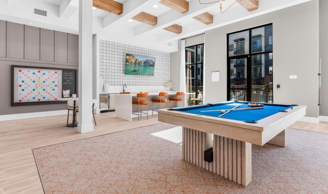 a clubhouse room with a pool table and large windows