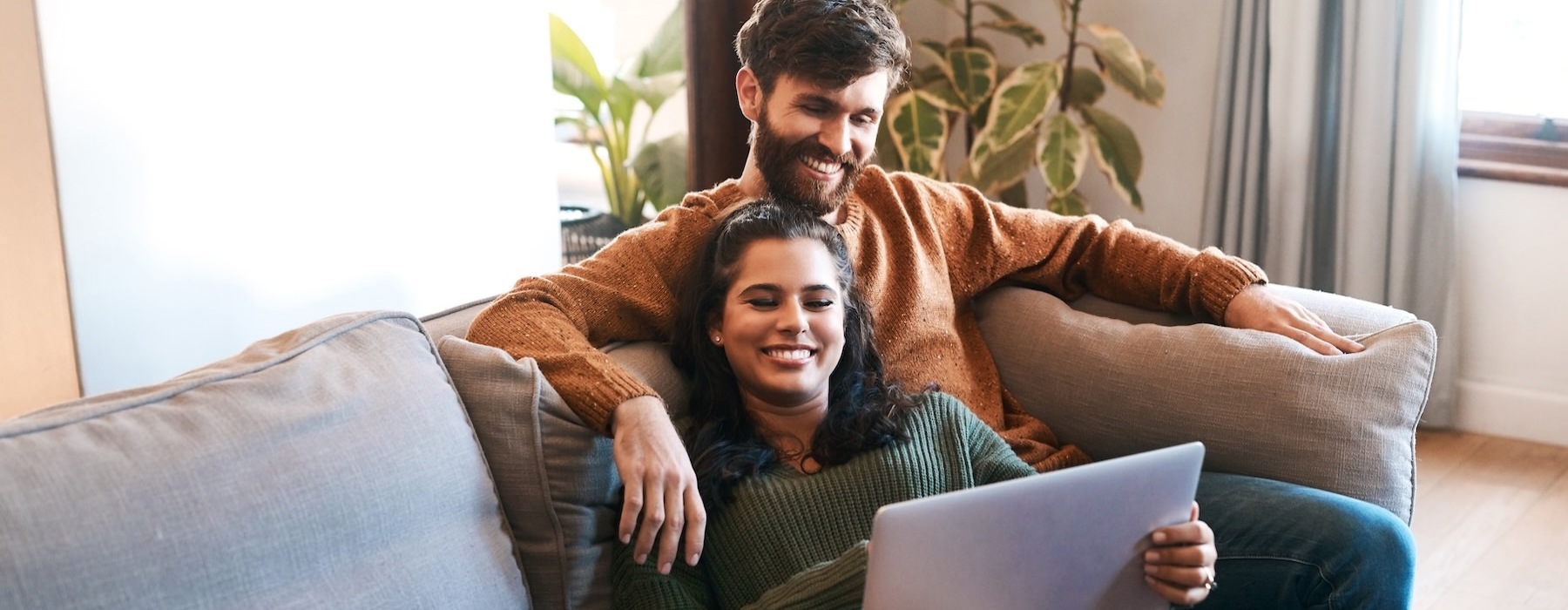a couple sitting on a couch with a laptop